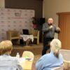 zaproszony gość stoi przed publicznością i mówi do mikrofonu