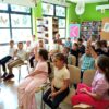 Dzieci siedzą na krzesłach i słuchają zaproszonej autorki
