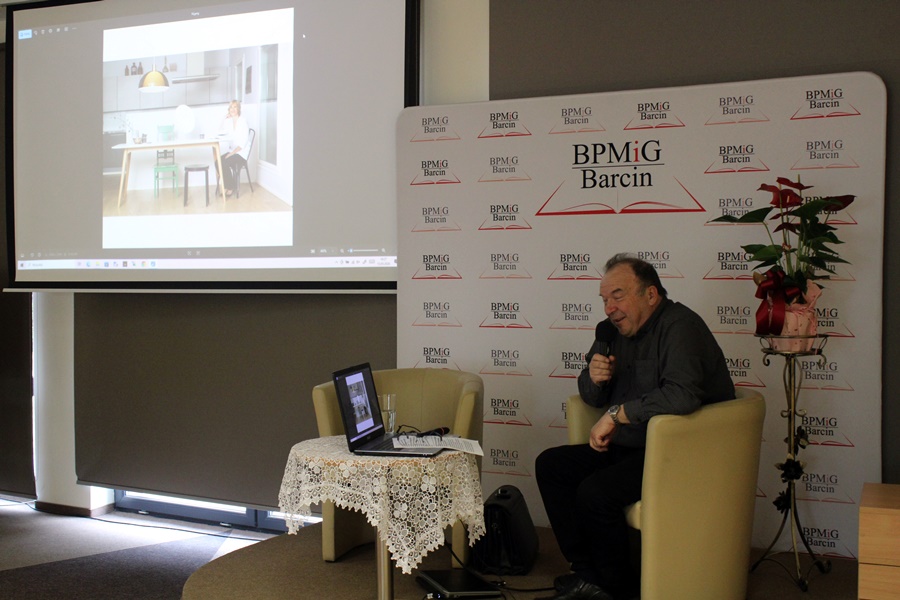 zaproszony autor siedzi na scenie, mówi do mikrofonu i przełącza przygotowaną prezentację