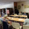 Uczestnicy DKK podczas rozmowy, siedzą przy stolikach popijają kawę lub herbatę.