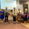 Nagrodzone osoby stoją przed zgromadzoną publicznością i słuchają podziękowań za swoją działalność