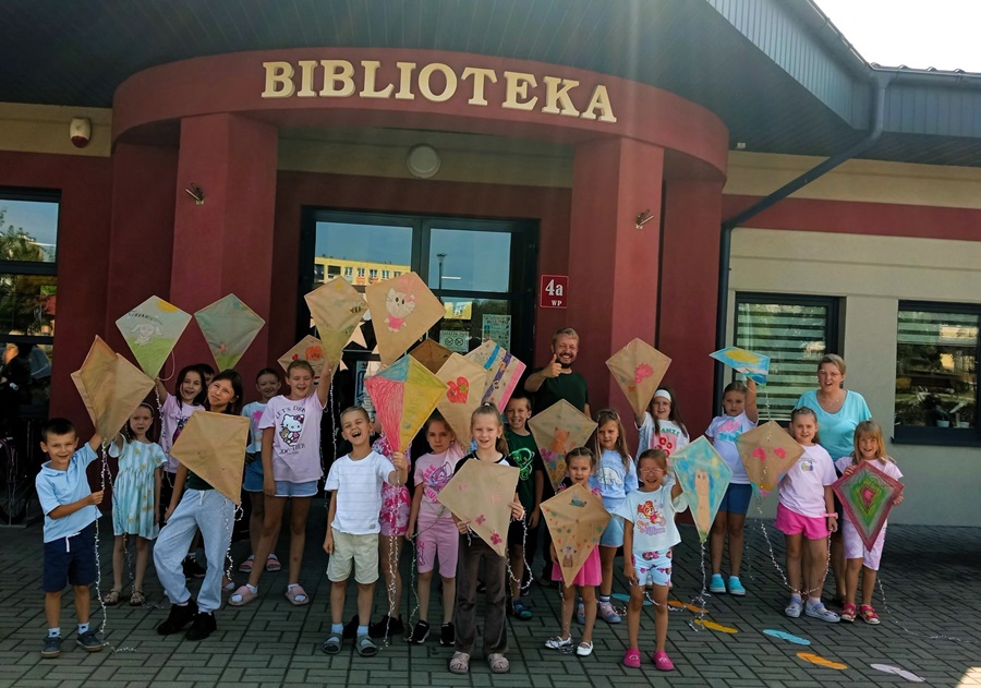 Grupowe zdjęcie uczestników i prowadzących warsztaty pzred budynkiem biblioteki w Barcinie